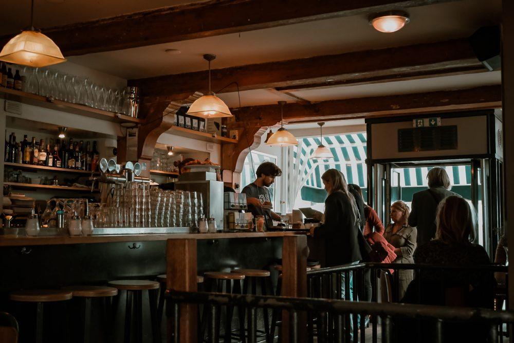 Interior de una cafetería con barra de madera y lámparas cálidas